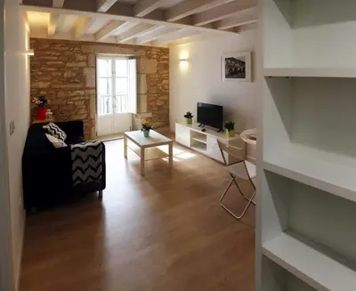 a living room with a couch a table and a tv at Puerta del Camino in Santiago de Compostela