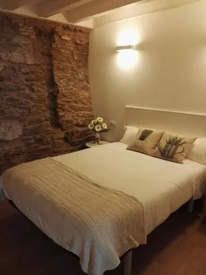 a bedroom with a large bed with a stone wall at Puerta del Camino in Santiago de Compostela