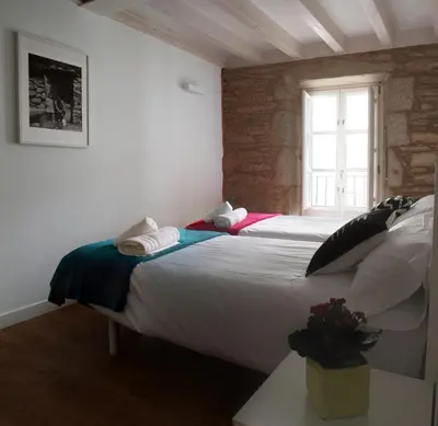 a bedroom with a large white bed with a window at Puerta del Camino in Santiago de Compostela
