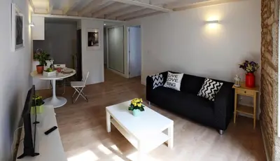 a living room with a black couch and a table at Puerta del Camino in Santiago de Compostela