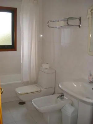 a white bathroom with a toilet and a sink at Hostal Pumar in Santiago de Compostela