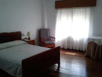 a bedroom with a bed and a chair and a window at Hostal Pumar in Santiago de Compostela