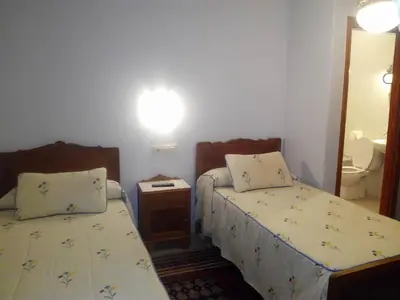 a small bedroom with two beds and a mirror at Hostal Pumar in Santiago de Compostela