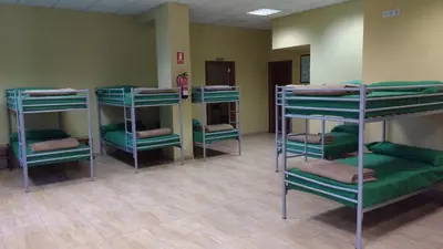a room with several bunk beds in a hospital at Albergue Los Caminantes 2 in Arzúa