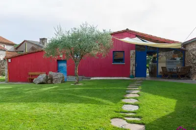 a red house with a tree in the yard at Casa de Amancio in Lavacolla