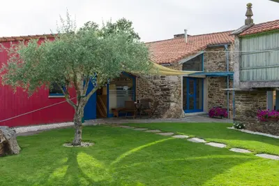 a stone house with a tree in the yard at Casa de Amancio in Lavacolla