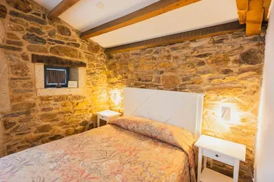 a stone walled bedroom with a bed in a room at Casa de Amancio in Lavacolla