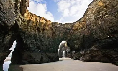 a rock wall with an archway in the water at Precioso Apartamento con Spa en Galicia / Playa Catedrales in Foz
