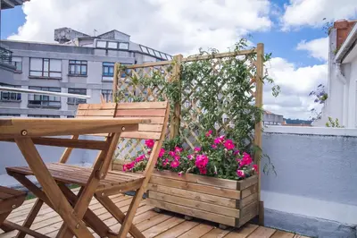 a wooden chair sitting on a balcony with flowers at Santiago Center Rooms in Santiago de Compostela