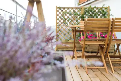 a wooden chair sitting on a porch with flowers at Santiago Center Rooms in Santiago de Compostela