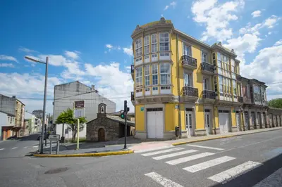 a yellow building on the corner of a street at La Posada de La Casona de Sarria in Sarria