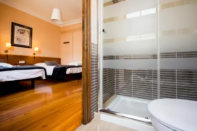 a bathroom with a shower and a toilet and a bedroom at La Posada de La Casona de Sarria in Sarria