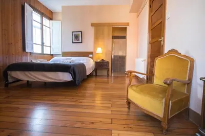 a bedroom with a bed and a chair at La Posada de La Casona de Sarria in Sarria