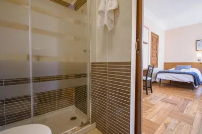 a bathroom with a shower and a bedroom at La Posada de La Casona de Sarria in Sarria