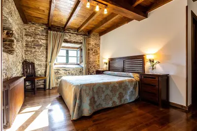 a bedroom with a bed and a wooden ceiling at Naturlar Casa do Cura in Beigondo