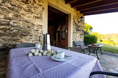a table with a purple table cloth on a patio at Naturlar Casa do Cura in Beigondo