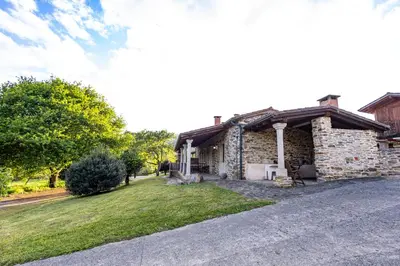 a stone house with a porch and a grass yard at Naturlar Don Benito in Arnego