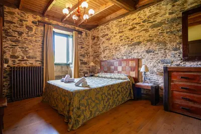 a bedroom with a bed in a room with stone walls at Naturlar Don Benito in Arnego