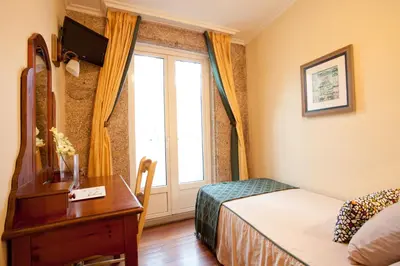 a bedroom with a bed and a desk and a window at Hotel Fonte de San Roque in Santiago de Compostela