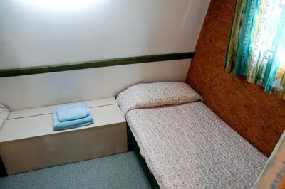 a small room with two beds and a window at Camping As Cancelas in Santiago de Compostela