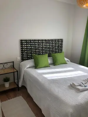 a bedroom with a bed with two green pillows at Pensión Fernández in Vega de Valcarce