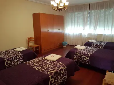 a hotel room with three beds and a chandelier at Pensión Garcia in Tríacastela