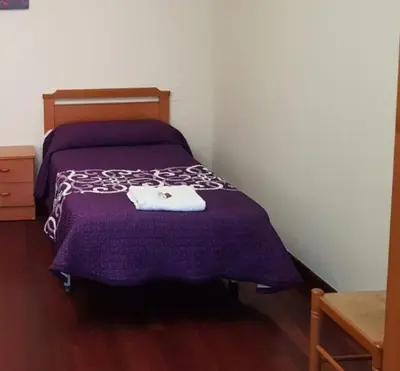 a bedroom with a purple bed with a towel on it at Pensión Garcia in Tríacastela