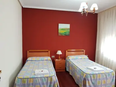 two beds in a room with red walls at Pensión Garcia in Tríacastela