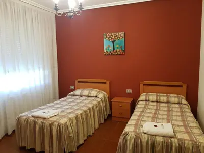 two beds in a room with red walls at Pensión Garcia in Tríacastela