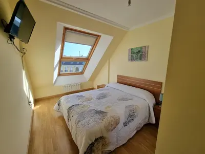 a bedroom with a bed and a window and a television at Dúplex en 1ª línea de playa in Foz