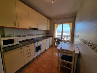 a kitchen with white cabinets and a table with a view at Dúplex en 1ª línea de playa in Foz