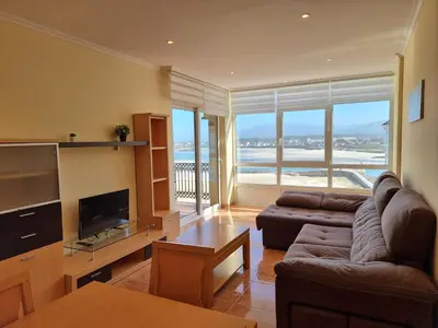 a living room with a couch and a tv at Dúplex en 1ª línea de playa in Foz