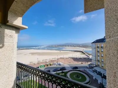 a balcony with a view of a beach and a building at Dúplex en 1ª línea de playa in Foz