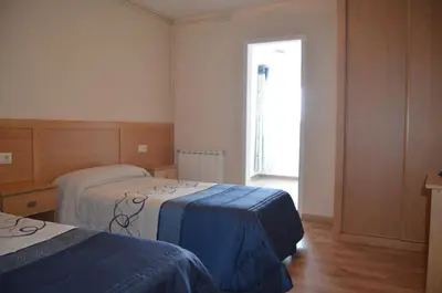 a hotel room with two beds and a window at Del Peregrino in Arzúa