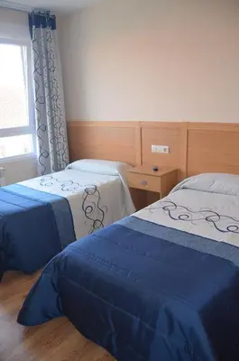 a bedroom with two beds and a window at Del Peregrino in Arzúa