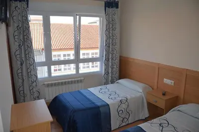 a bedroom with two beds and a large window at Del Peregrino in Arzúa