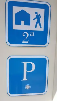 a blue sign with a man walking in front of a parking sign at Del Peregrino in Arzúa