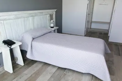 a bedroom with a white bed and two tables at Hotel Mica in Palas de Rei