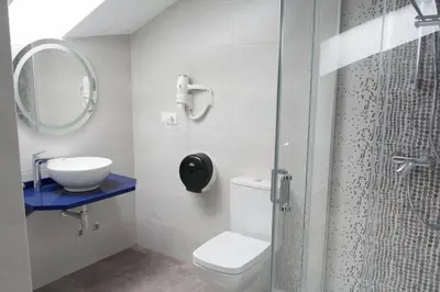 a bathroom with a toilet and a sink and a shower at Hotel Mica in Palas de Rei