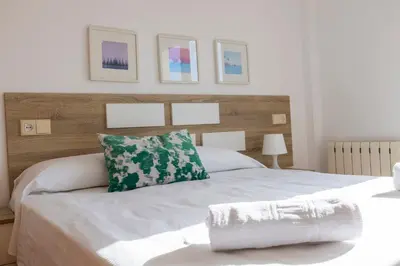 a bedroom with a white bed with a wooden headboard at Apartagal-Edificio Celtas Foz in Foz