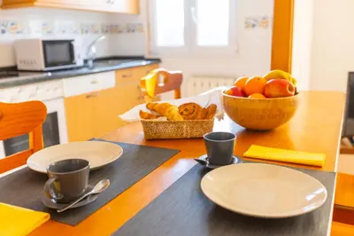 a table with plates and cups and a bowl of fruit at Apartagal-Edificio Celtas Foz in Foz