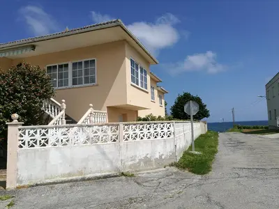 a house with a white fence in front of it at Chalet vacacional en segunda linea de playa in Foz