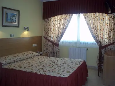 a bedroom with a bed and a large window at Hotel Suiza in Arzúa