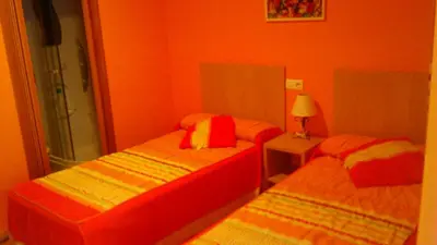 two beds in a room with orange walls at pension compas in O Pedrouzo