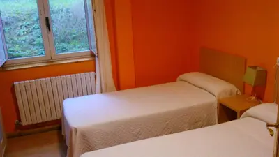 a room with two beds and a window at pension compas in O Pedrouzo