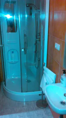 a shower with a glass door next to a sink at pension compas in O Pedrouzo