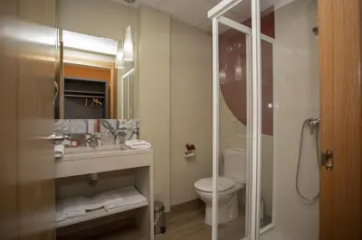 a bathroom with a toilet and a glass shower at Hotel Novoa in Sarria