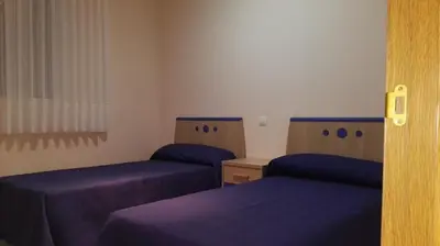 two beds in a room with purple sheets at Apartamentos Rapadoira in Foz