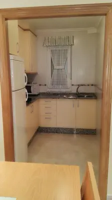 a kitchen with a white refrigerator and a window at Apartamentos Rapadoira in Foz