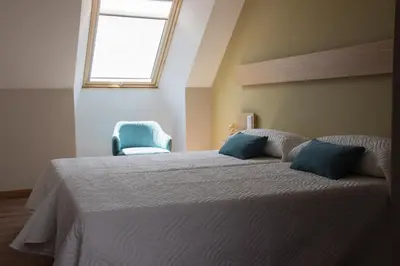 a bedroom with a bed with a window and a chair at Casona da Ponte in Portomarin